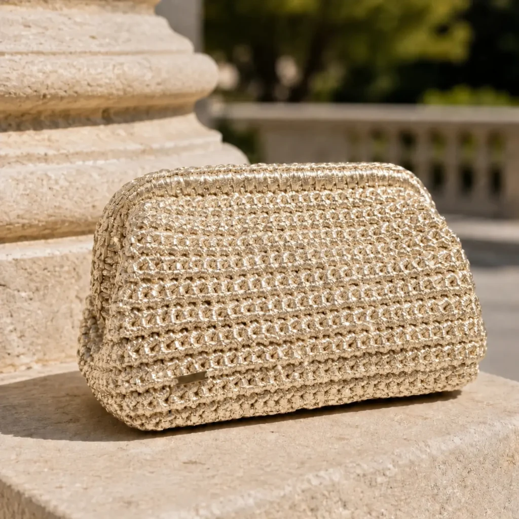 Bolso de mano dorado Melek en crochet metalizado artesanal sobre piedra clara.