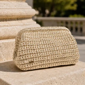 Bolso de mano dorado Melek en crochet metalizado artesanal sobre piedra clara.