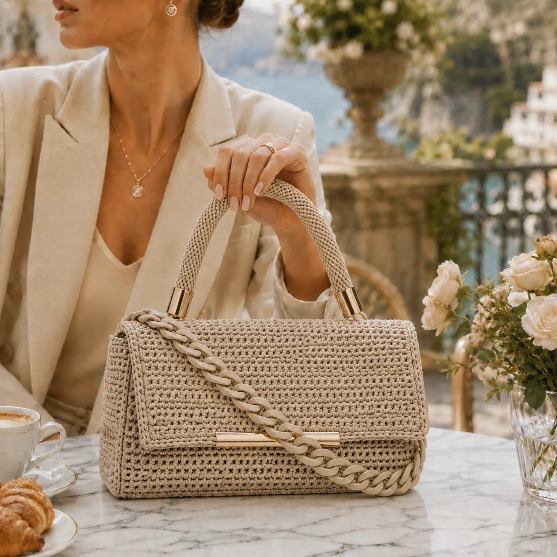 Bolso vegano de lujo Meryem en crochet beige, con asa superior, cadena decorativa y herrajes dorados.