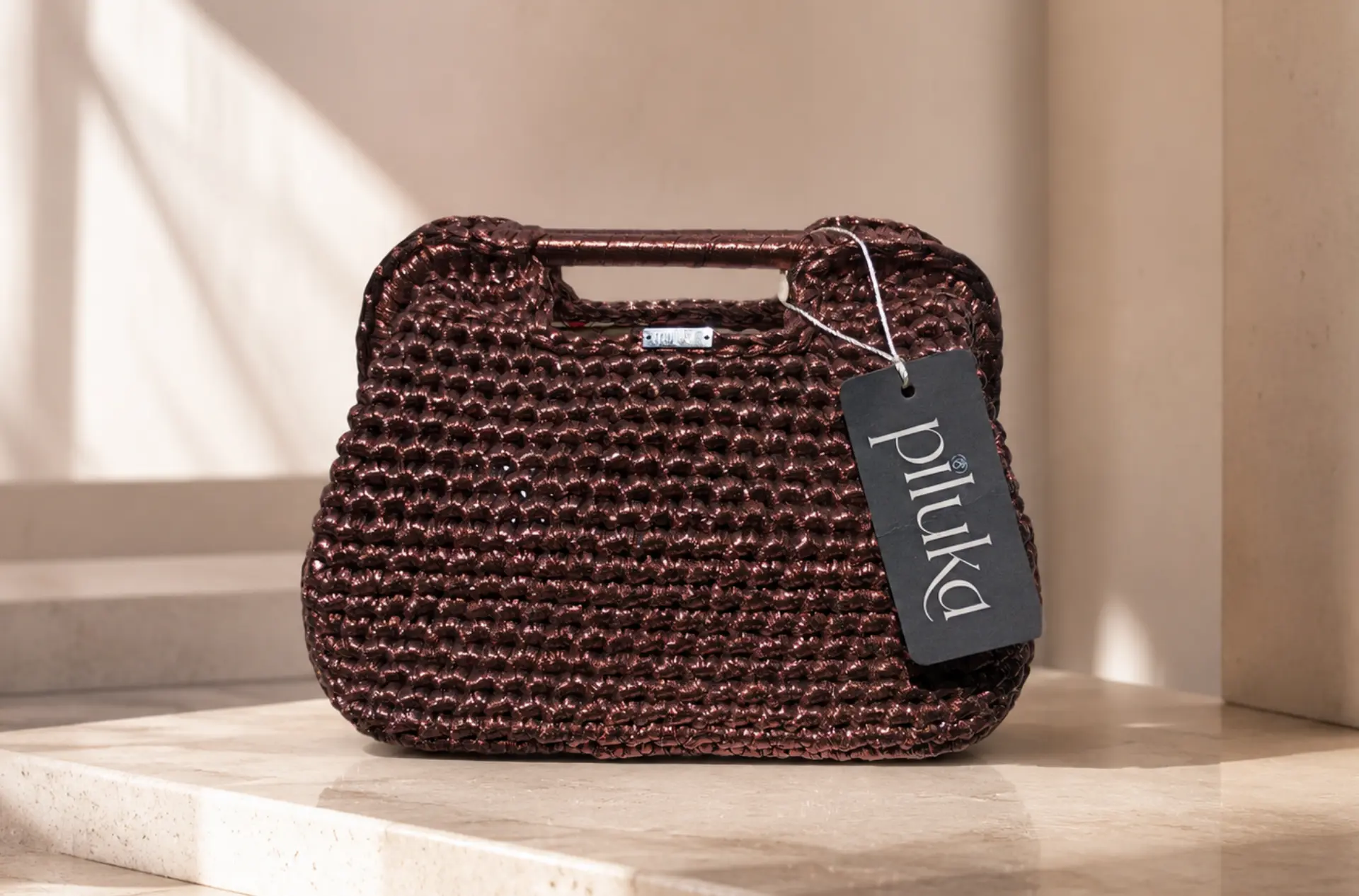 Bolso de crochet cobre con asa superior y etiqueta Piluka.