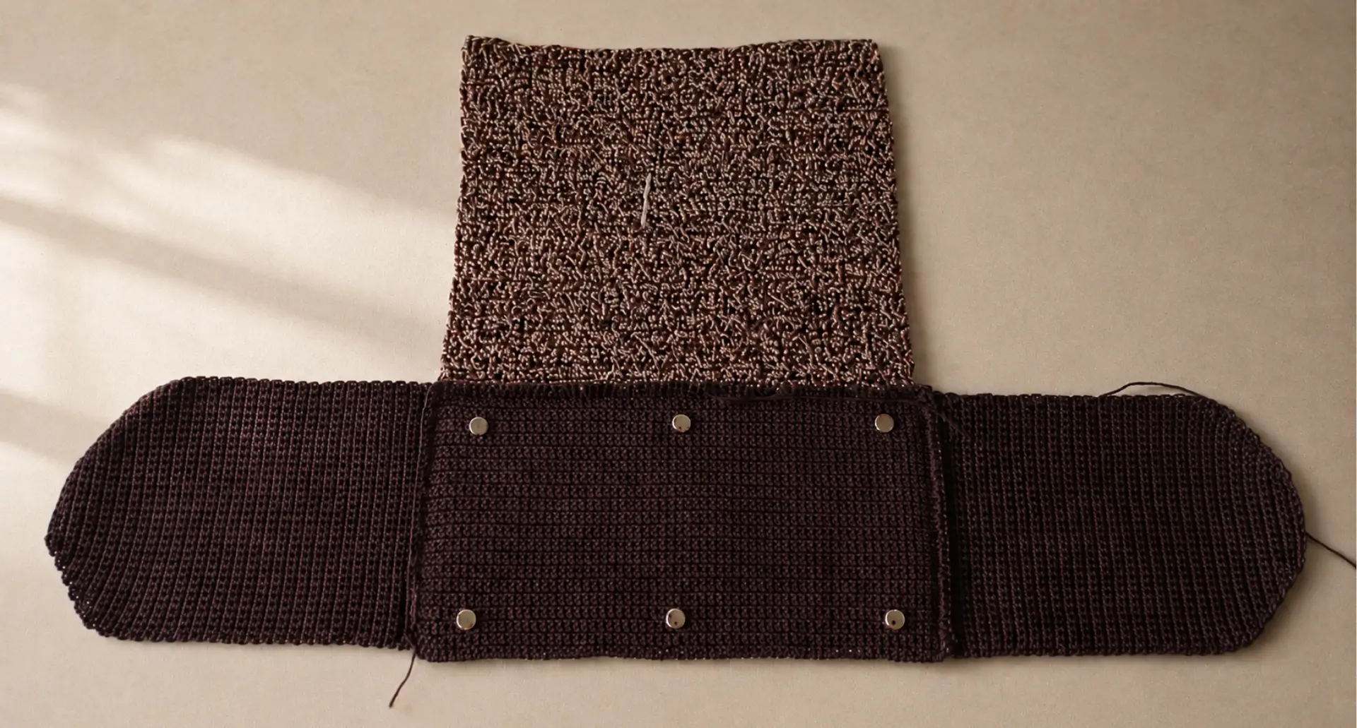 Pieza de crochet del bolso Elif en proceso artesanal sobre una superficie cálida.